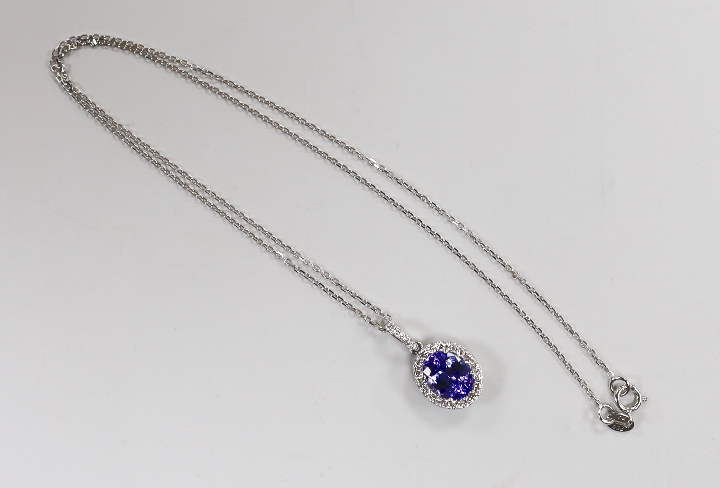 A modern 18k white metal, tanzanite and diamond set oval cluster pendant, 20mm, on a 750 fine link chain, 39cm, gross weight 3.2 grams, the tanzanite weighing approx. 1.70ct, the diamonds totalling approx. 0.50ct